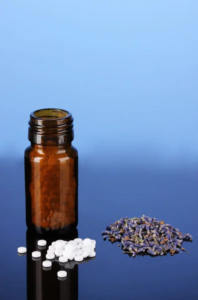 Lahvičku s prášky a byliny na modrém pozadí. koncepce homeopatie — Stock fotografie