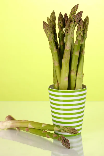 Fresh asparagus in colorful pot on green background — Stock Photo, Image