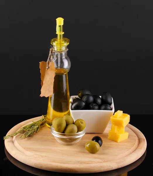 Černé a zelené olivy v misce s rozmarýnem, olivovým olejem a sýrem na palubě — Stock fotografie
