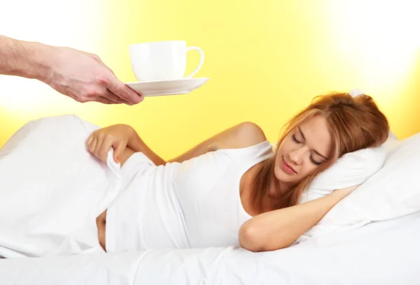 Café de la mañana en la cama para mujer joven sobre fondo amarillo — Foto de Stock