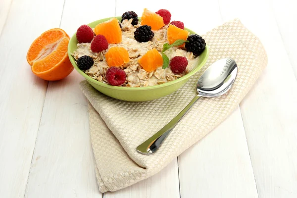 Tasty oatmeal with berries and fruits, on white wooden table — Stock Photo, Image