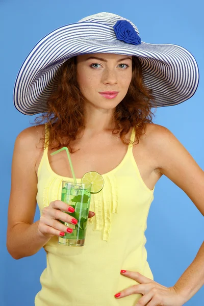 Uśmiechający się piękna dziewczyna z plaży kapelusz i koktajl na niebieskim tle — Zdjęcie stockowe