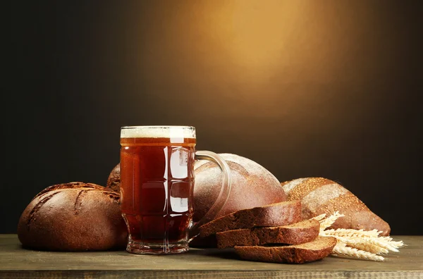 Tankard svagdricka och råg bröd med öron, på träbord på brun backgro — Stockfoto
