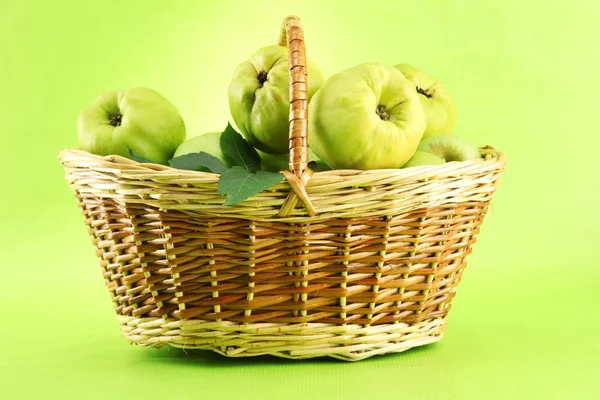 Süße Quitten mit Blättern im Korb, auf grünem Hintergrund — Stockfoto