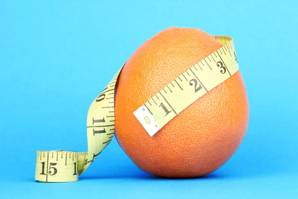 Naranja con cinta métrica sobre fondo azul —  Fotos de Stock