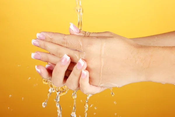 Lavar as mãos da mulher no fundo laranja close-up — Fotografia de Stock