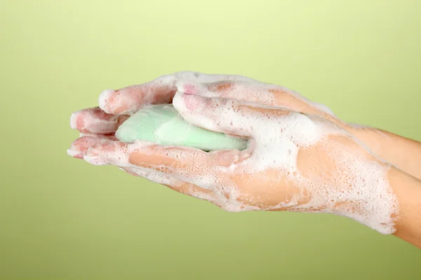 Woman's hands in soapsuds, on green background close-up — Stock Photo, Image