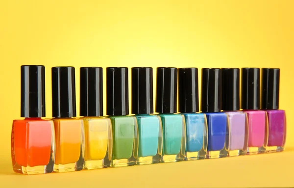 Grupo de esmaltes de uñas brillantes, sobre fondo amarillo —  Fotos de Stock