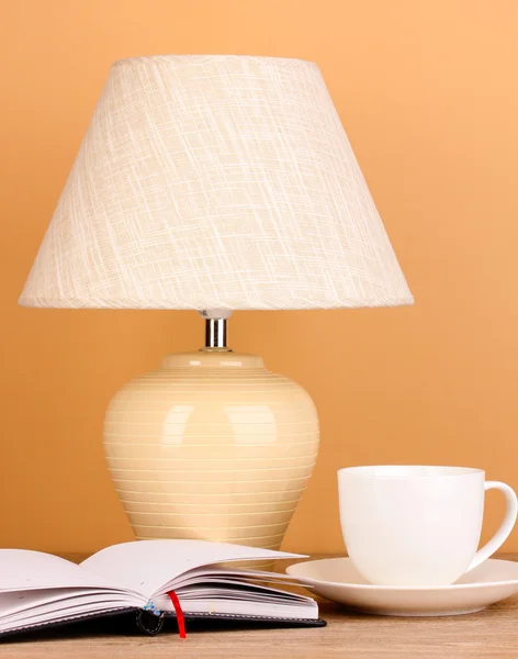 Table lamp and cup on beige background — Stock Photo, Image