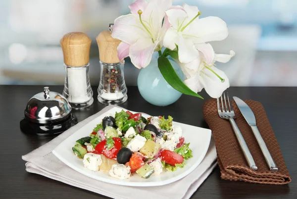 Fresh greek salad on white plate on table on restaurant background — Stock Photo, Image