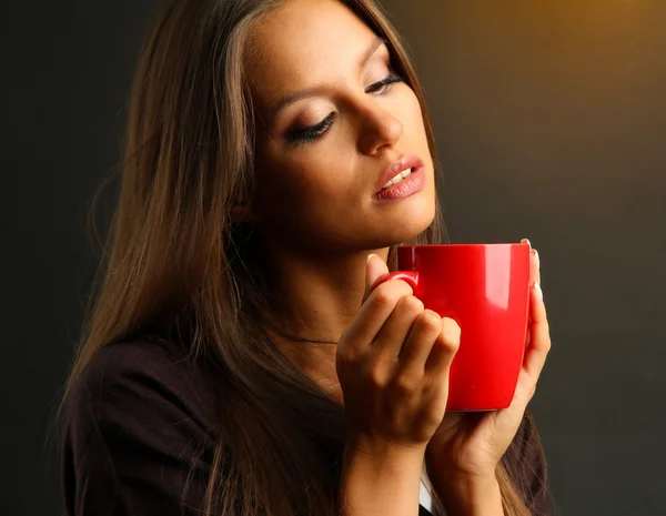 Bella giovane donna con tazza di caffè, su sfondo marrone — Foto Stock