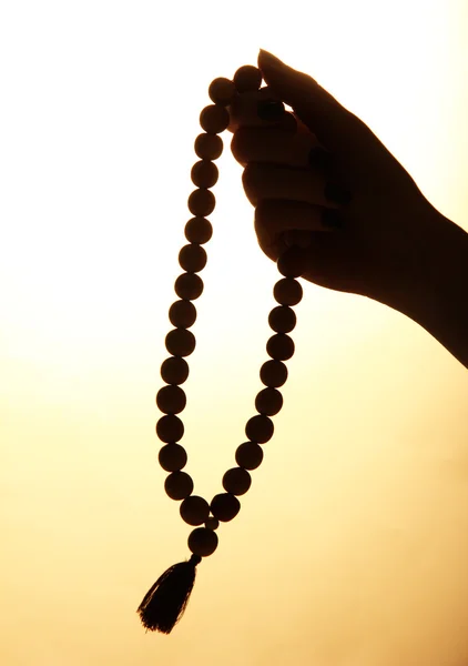 Manos femeninas con rosario, sobre fondo beige — Foto de Stock