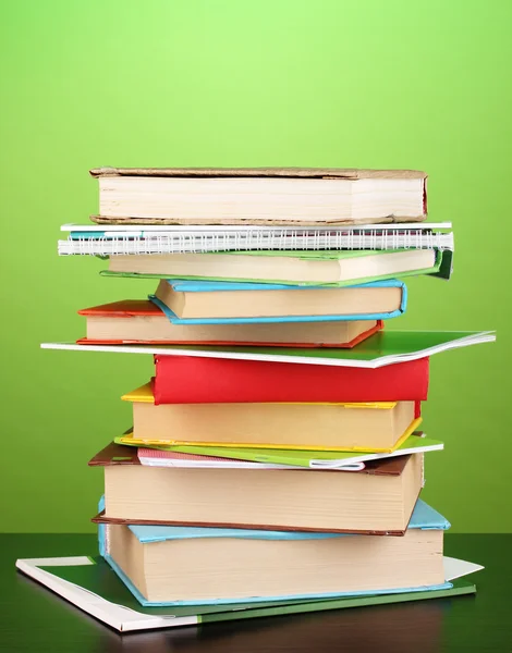 Stos ciekawych książek i czasopism na drewnianym stole na zielony deseń — Zdjęcie stockowe