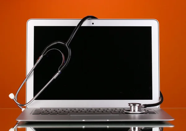 Silver notebook with a stethoscope on red background with reflection — Stock Photo, Image