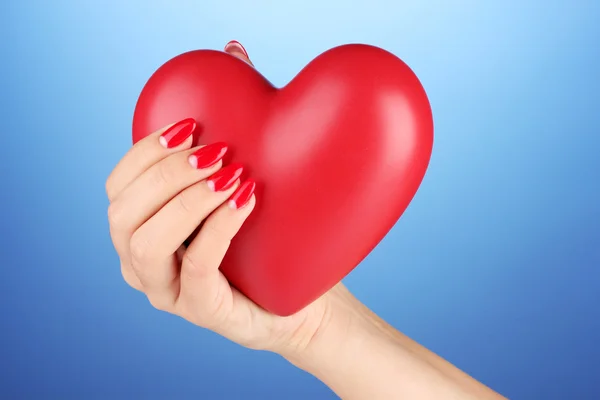 Corazón rojo en la mano de la mujer sobre fondo de color —  Fotos de Stock