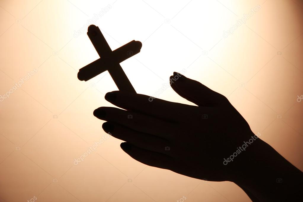 female hands with crucifix, on brown background