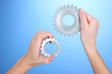 Metalik cogwheels mavi zemin üzerine onun elinde tutan adam