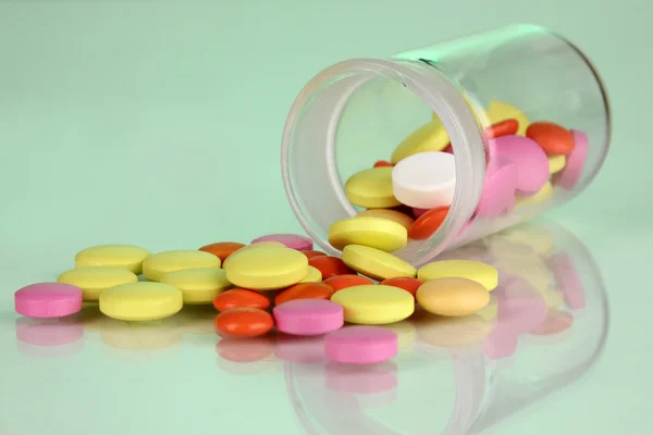 Pillole in recipiente su sfondo verde — Foto Stock