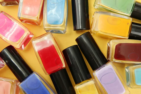 Group of bright nail polishes, on yellow background — Stock Photo, Image