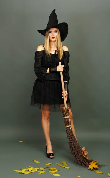 Хэллоуинская ведьма с метлой на сером фоне — стоковое фото