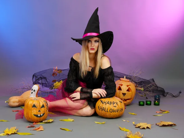 Halloween witch with pumpkins on color background — Stock Photo, Image