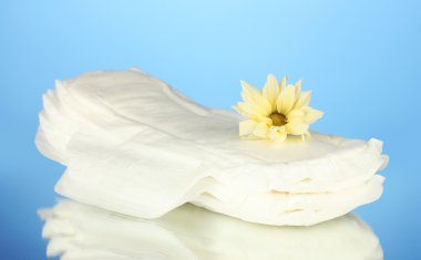 Panty liners and yellow flower on blue background close-up clipart