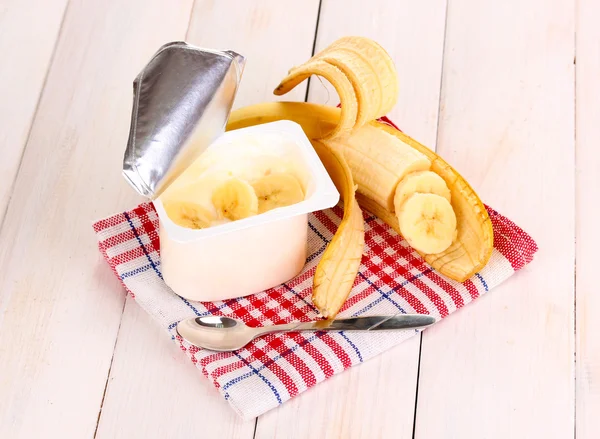 Yogurt with banana on wooden background — Stock Photo, Image