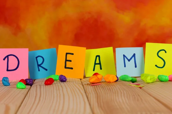 Slovo sny na dřevěný stůl na akvarel oranžové pozadí — Stock fotografie