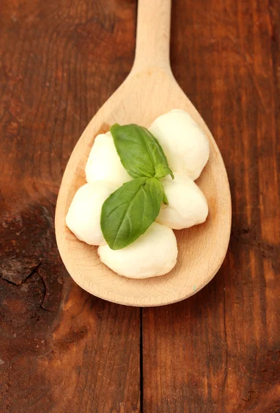 Cheese mozzarella with green basil in wooden spoon on wooden background clo — Stock Photo, Image