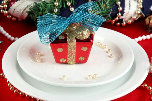 Small Christmas gift on plate on serving Christmas table background close-u — Stock Photo, Image