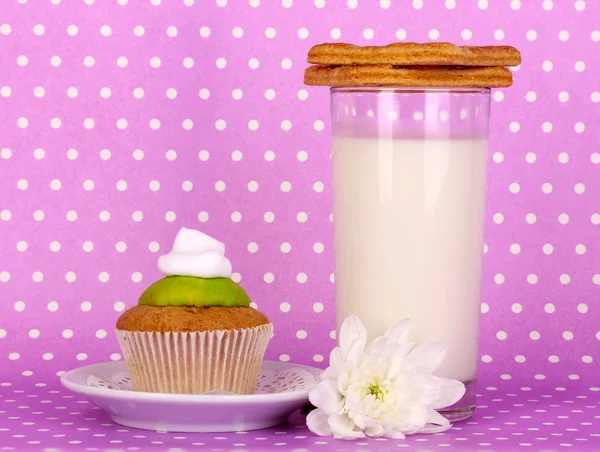 Glass of fresh new milk with confectionery on purple polka dot background — Stock Photo, Image