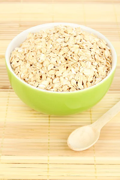 Cuenco verde lleno de copos de avena con cuchara de madera —  Fotos de Stock