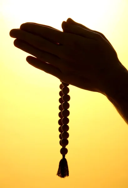 Male hands with rosary, on yellow background — Stock Photo, Image