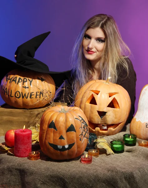 Halloween heks met pumpkins op kleur achtergrond — Stockfoto