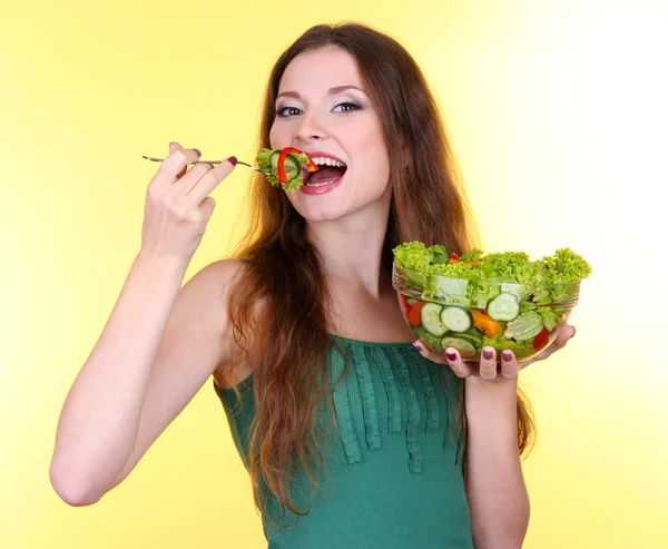 Mulher bonita com salada de legumes no fundo amarelo — Fotografia de Stock