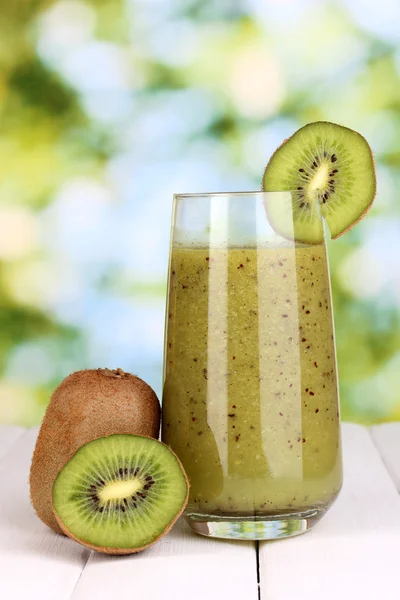 Glass of fresh kiwi juice on wooden table, on green background — Stock Photo, Image