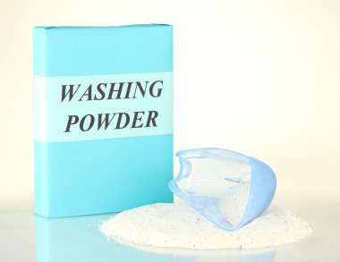 Box of washing powder with blue measuring cup, isolated on white clipart