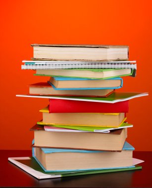 Stack of interesting books and magazines on wooden table on red background clipart