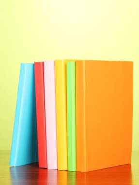 yeşil zemin üzerine çok renkli kitap yığını