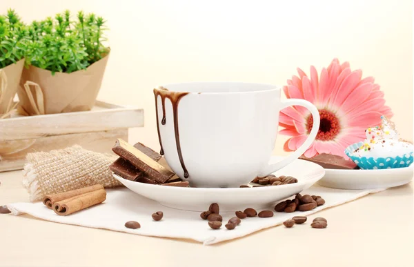 Dirty cup of coffee and gerbera beans, cinnamon sticks on wooden table — Stock Photo, Image