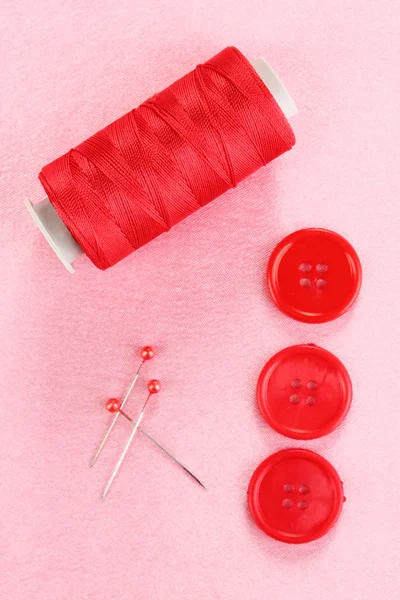 Colorful sewing buttons with thread on pink fabric — Stock fotografie