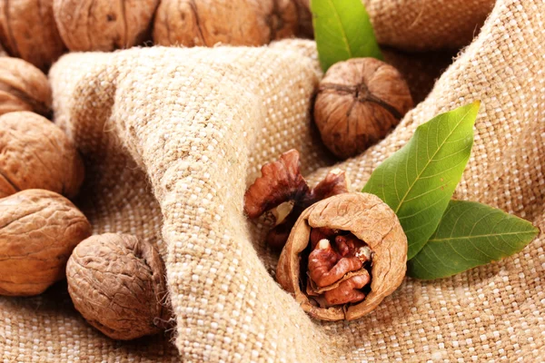 Vlašské ořechy se zelenými listy, na pozadí pytlovina — Stock fotografie