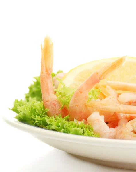 Crevettes bouillies avec des feuilles de citron et de laitue sur l'assiette, isolées sur blanc — Photo