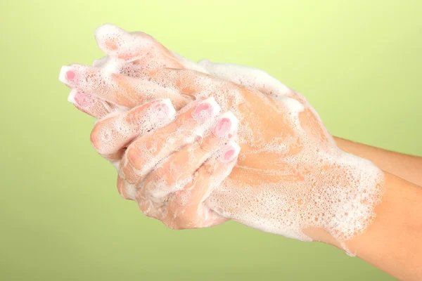 Soapsuds 녹색 배경 클로즈업에 있는 여자의 손 — 스톡 사진