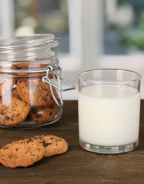 Glas mjölk med cookies på träbord på windows bakgrund närbild — Stockfoto