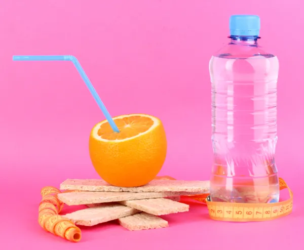 Laranjas maduras, vadias e garrafa de água como símbolo da dieta no fundo rosa — Fotografia de Stock