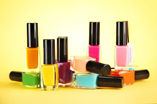 Grupo de esmaltes de uñas brillantes, sobre fondo amarillo —  Fotos de Stock