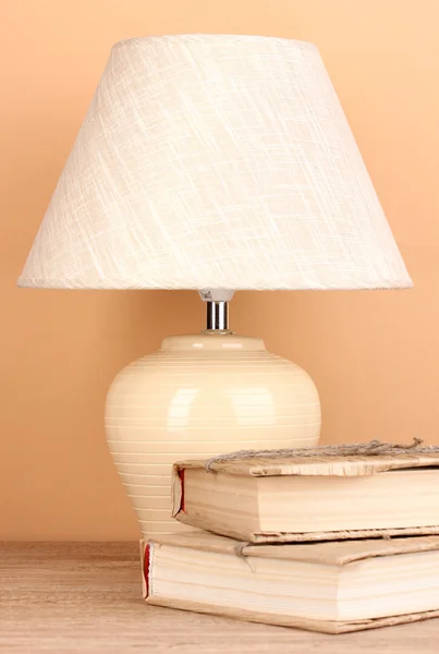 Table lamp and books on beige background — Stock Photo, Image