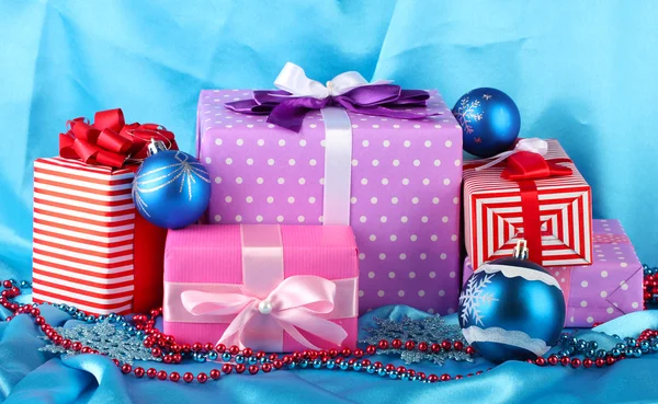 Colorful gifts with blue Christmas balls, snowflakes and beads on blue background — Stock Photo, Image