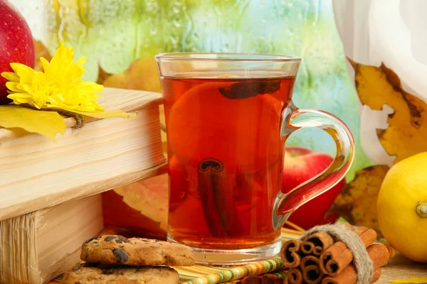 Xícara de chá quente e folhas de outono, na mesa de madeira — Fotografia de Stock